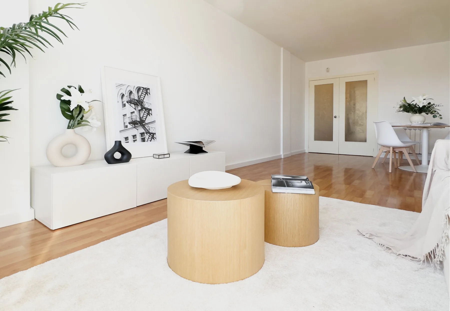 Salón blanco con mesas de roble y lámina en blanco y negro